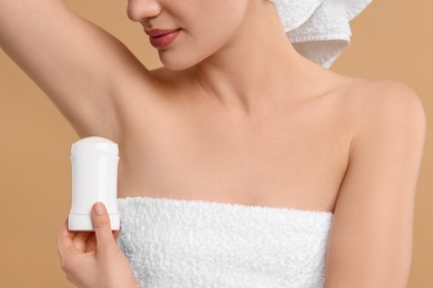 Photo of Woman applying deodorant on beige background, closeup