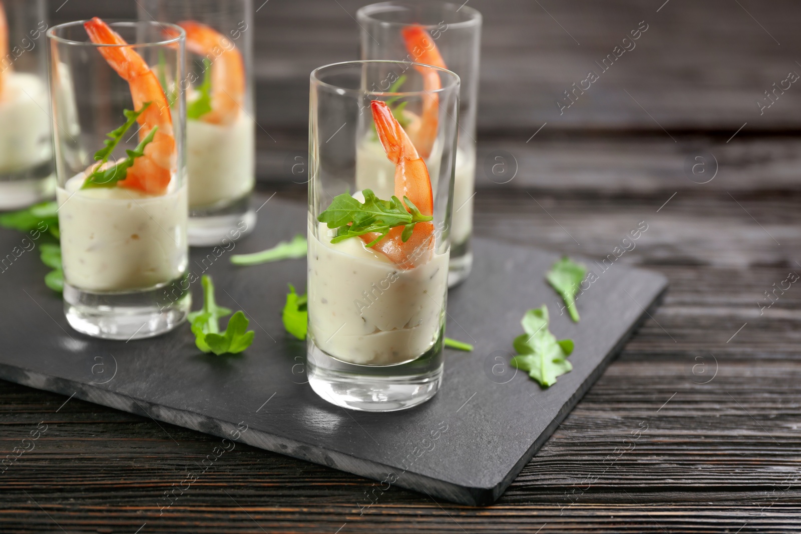 Photo of Delicious shrimp cocktail with tartar sauce served on black wooden table