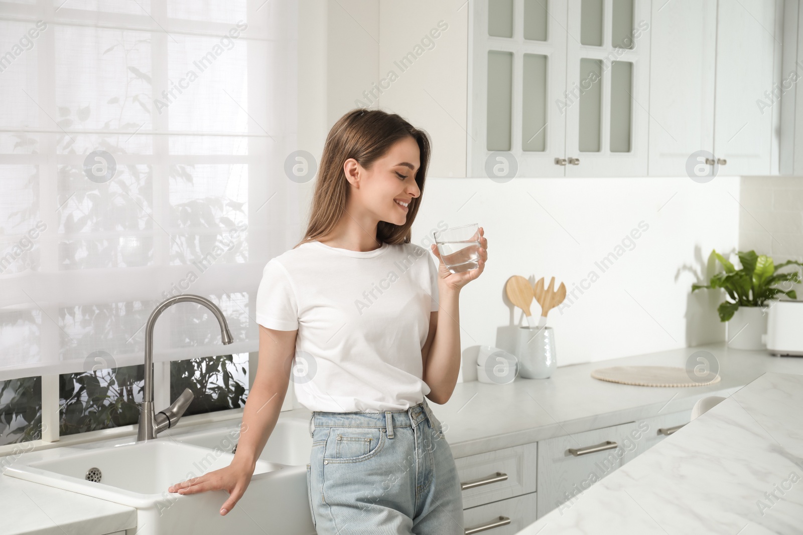 Photo of Woman drinking tap water from glass in kitchen