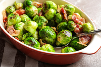 Photo of Delicious Brussels sprouts with bacon in baking dish on table, closeup