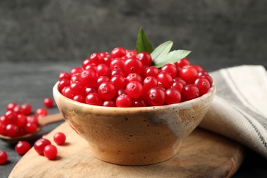 Photo of Tasty ripe cranberries on wooden board, closeup