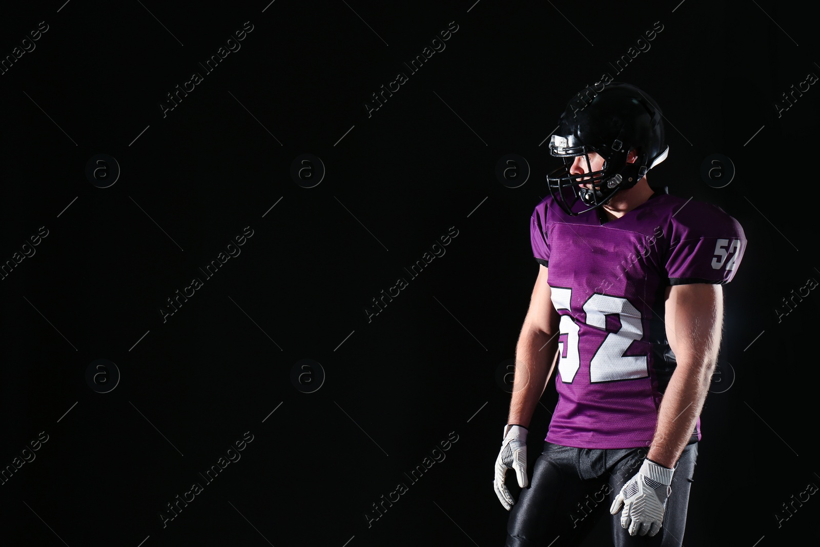 Photo of American football player wearing uniform on dark background. Space for text