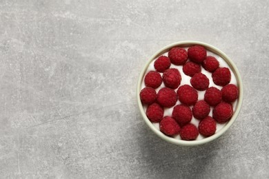 Photo of Bowl with delicious yogurt and raspberries on grey table, top view. Space for text