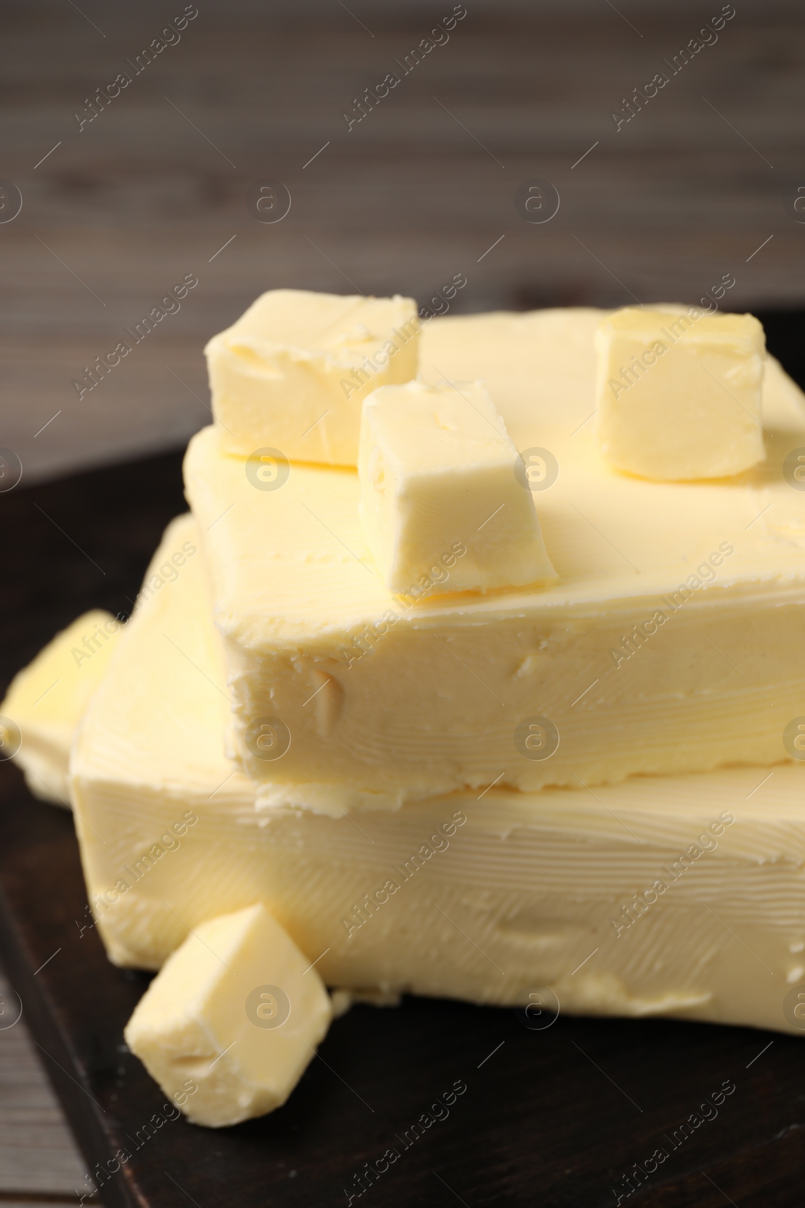 Photo of Pieces of tasty butter on wooden table, closeup