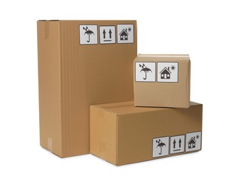 Photo of Many closed cardboard boxes with packaging symbols on white background. Delivery service