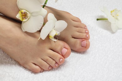 Woman with neat toenails after pedicure procedure on white terry towel, closeup