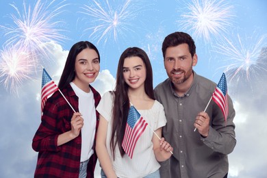 Image of 4th of July - Independence day of America. Happy family holding national flags of United States against sky with fireworks