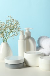 Photo of Different bath accessories and gypsophila on white table against light blue background