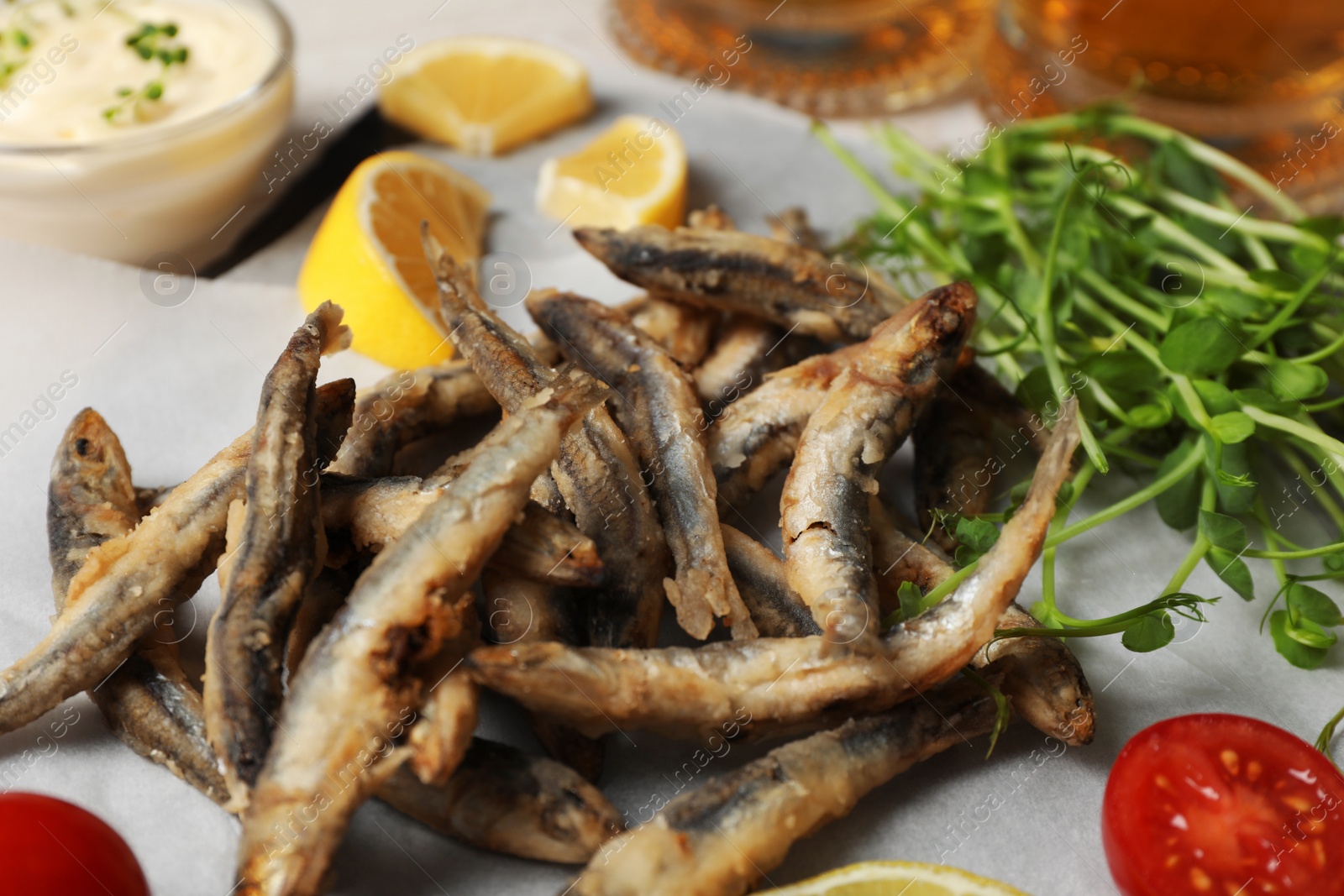 Photo of Delicious fried anchovies, microgreens and tomatoes, closeup view