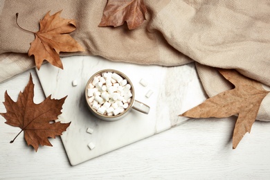 Flat lay composition with hot cozy drink and autumn leaves on wooden background