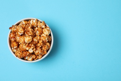 Bowl with caramel popcorn and space for text on color background, top view