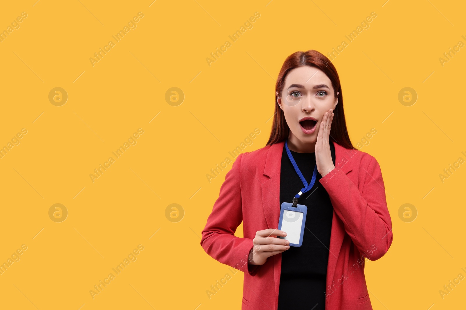 Photo of Shocked woman holding vip pass badge on orange background, space for text