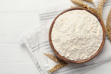 Bowl of organic wheat flour on white wooden table, flat lay. Space for text