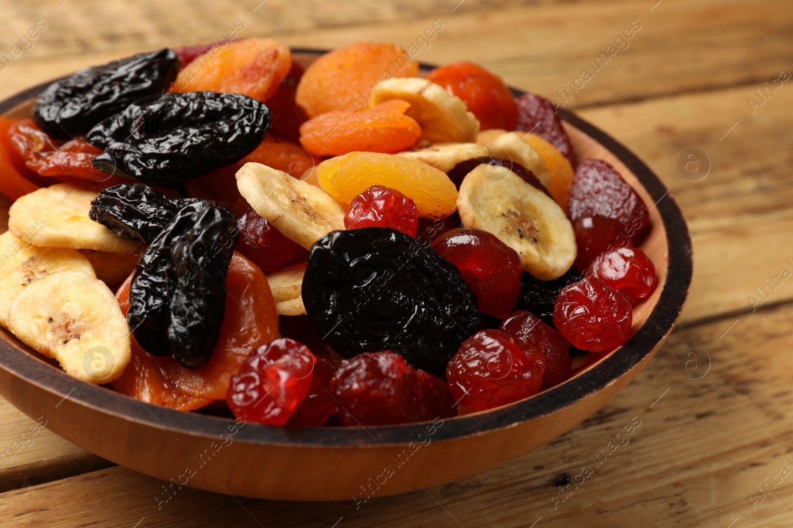 Photo of Mix of delicious dried fruits on wooden table, closeup