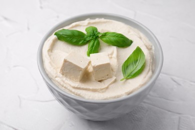 Delicious tofu sauce and basil leaves on white textured table, closeup