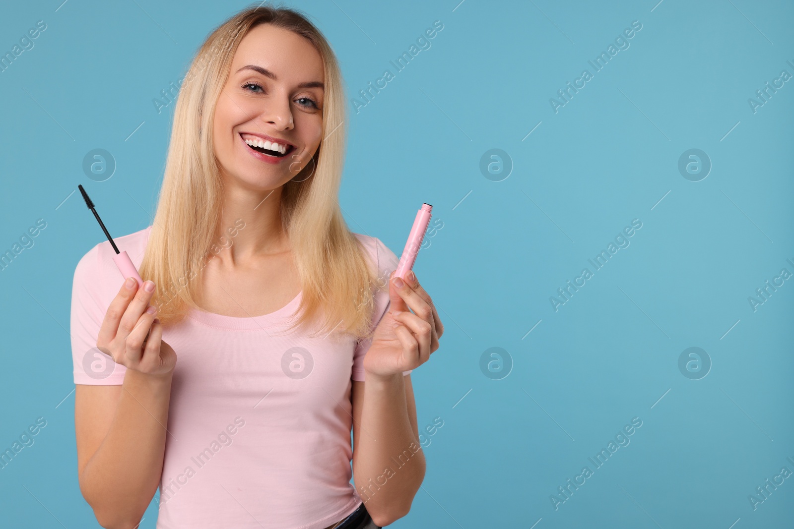 Photo of Beautiful woman with mascara on light blue background, space for text