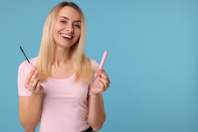 Beautiful woman with mascara on light blue background, space for text