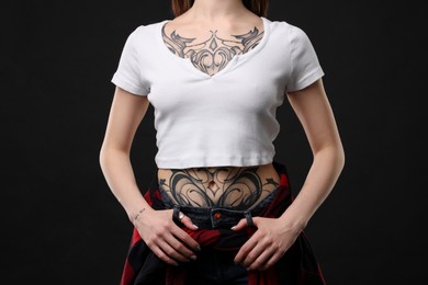 Photo of Woman with cool tattoos on black background, closeup