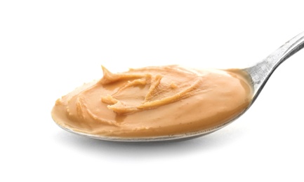 Photo of Creamy peanut butter in spoon on white background