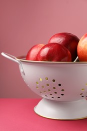 Photo of Colander with fresh apples on color background, closeup