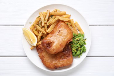 Photo of Tasty fish, chips, peas and lemon on white wooden table, top view