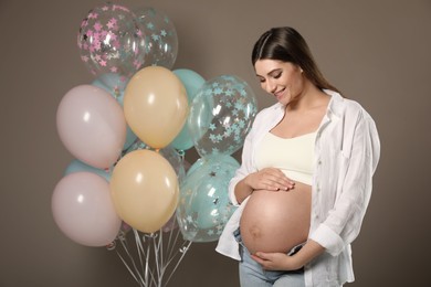 Photo of Happy pregnant woman with balloons near dark wall. Baby shower party