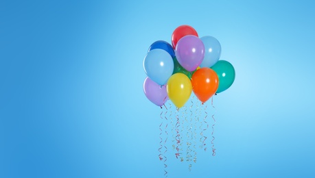 Photo of Many bright balloons floating on color background. Space for text