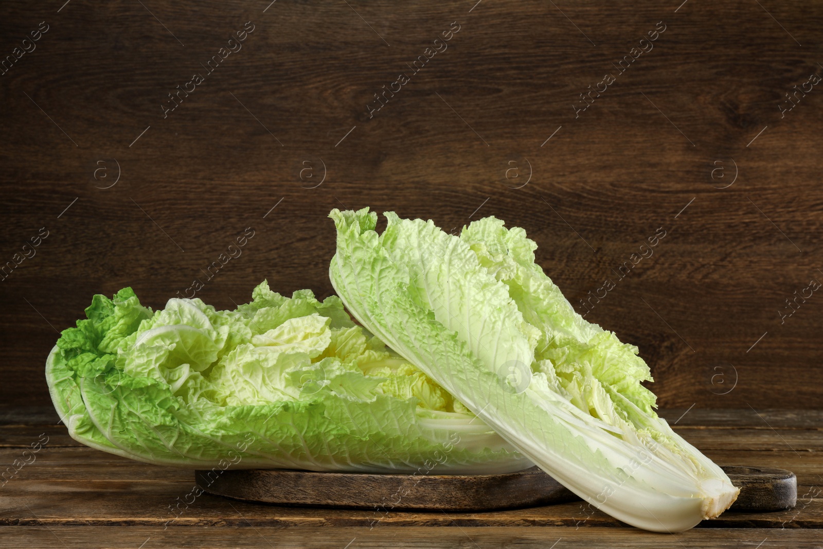 Photo of Cut fresh ripe Chinese cabbage on table against wooden background