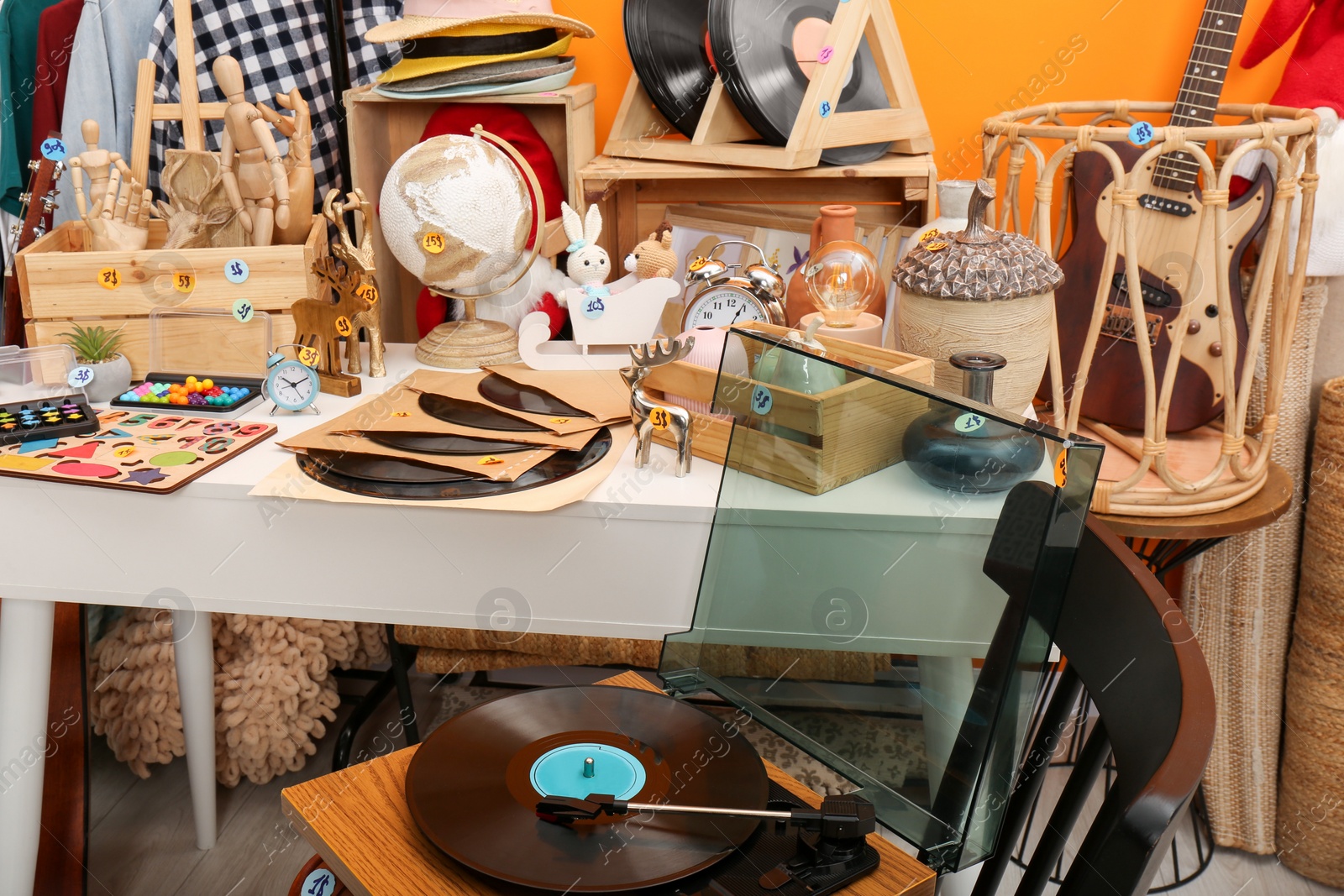 Photo of Many different stuff near orange wall indoors. Garage sale