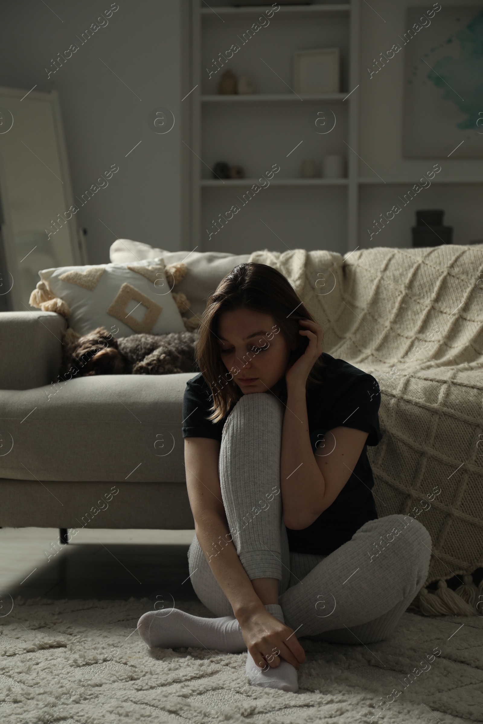 Photo of Sad young woman and her dog at home