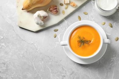 Delicious pumpkin soup in bowl on marble table, flat lay. Space for text