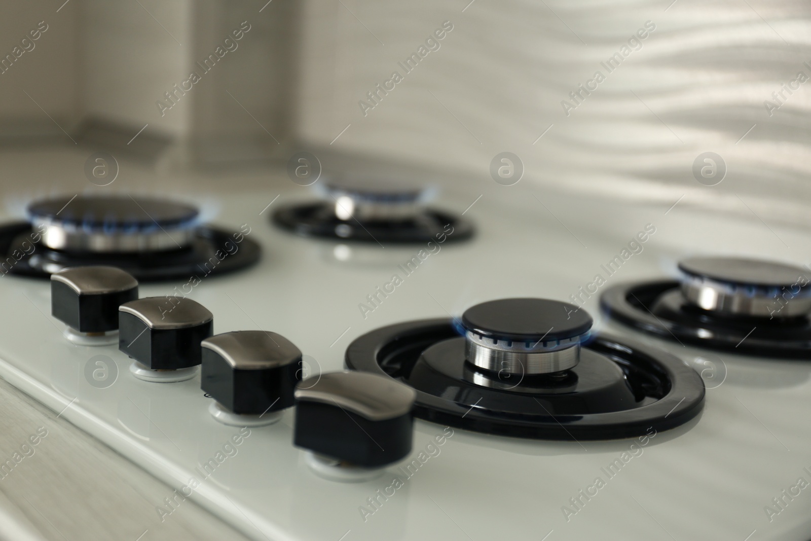 Photo of Gas burners with blue flame on modern stove