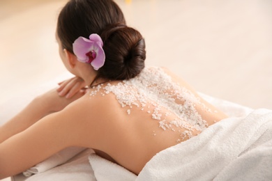 Beautiful young woman with body scrub on her back in spa salon