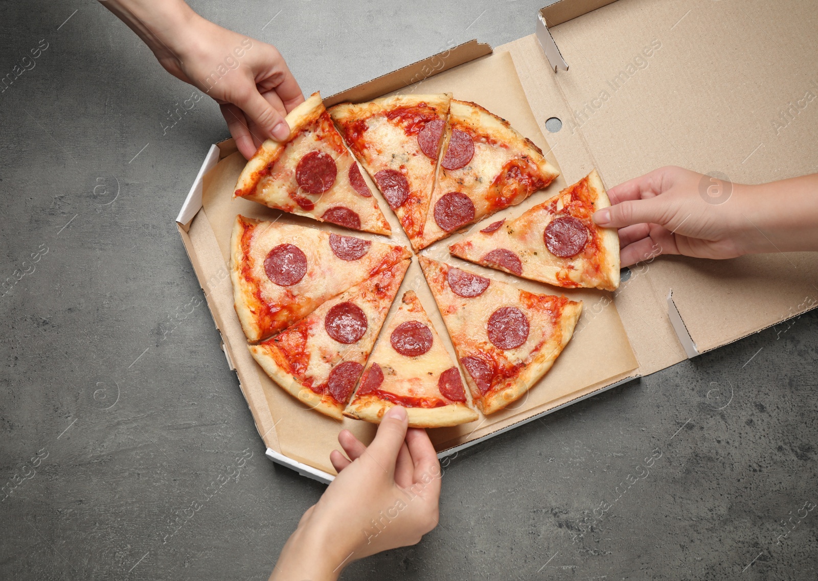 Photo of People taking slices of tasty pepperoni pizza at grey table, top view