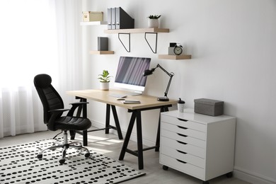 Photo of Comfortable office chair near table with modern computer