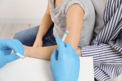 Children's hepatitis vaccination. Mother with her daughter in clinic. Doctor giving injection to little girl, closeup