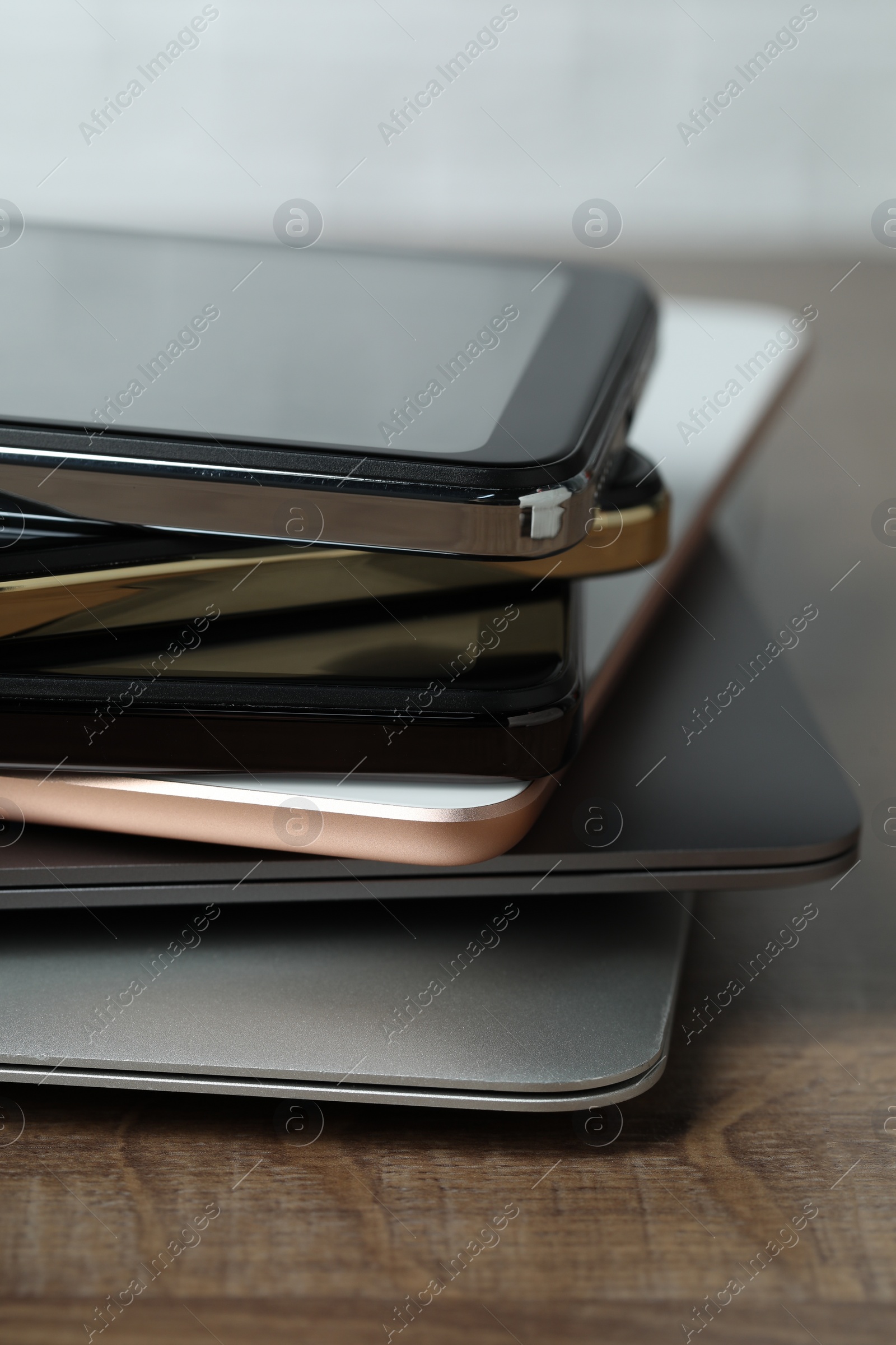 Photo of Stack of electronic devices on wooden table, closeup