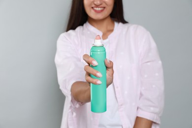 Photo of Woman with dry shampoo bottle on light grey background, closeup