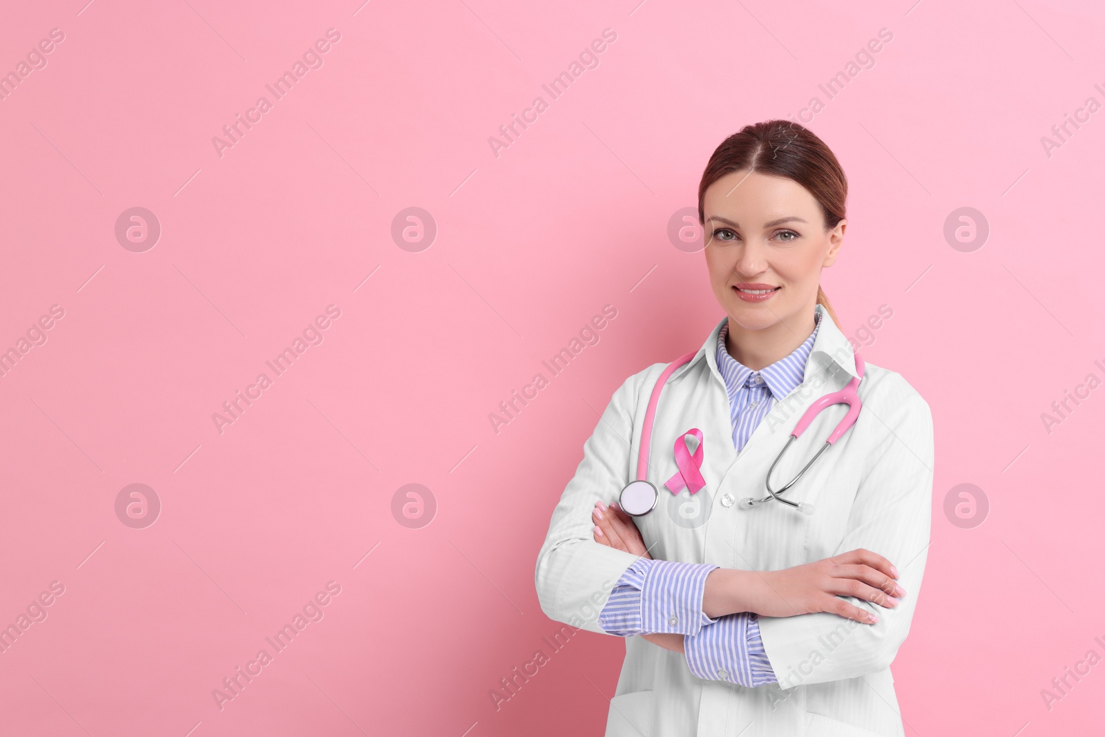 Photo of Mammologist with pink ribbon on color background, space for text. Breast cancer awareness