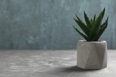 Photo of Beautiful artificial plant in flower pot on grey stone table. Space for text