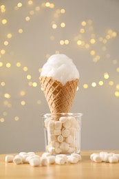 Photo of Sweet cotton candy in waffle cone and marshmallows on table against blurred lights