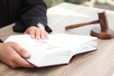 Photo of Judge with book at table indoors, closeup. Criminal law