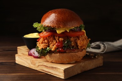 Photo of Delicious burger with crispy chicken patty on wooden table