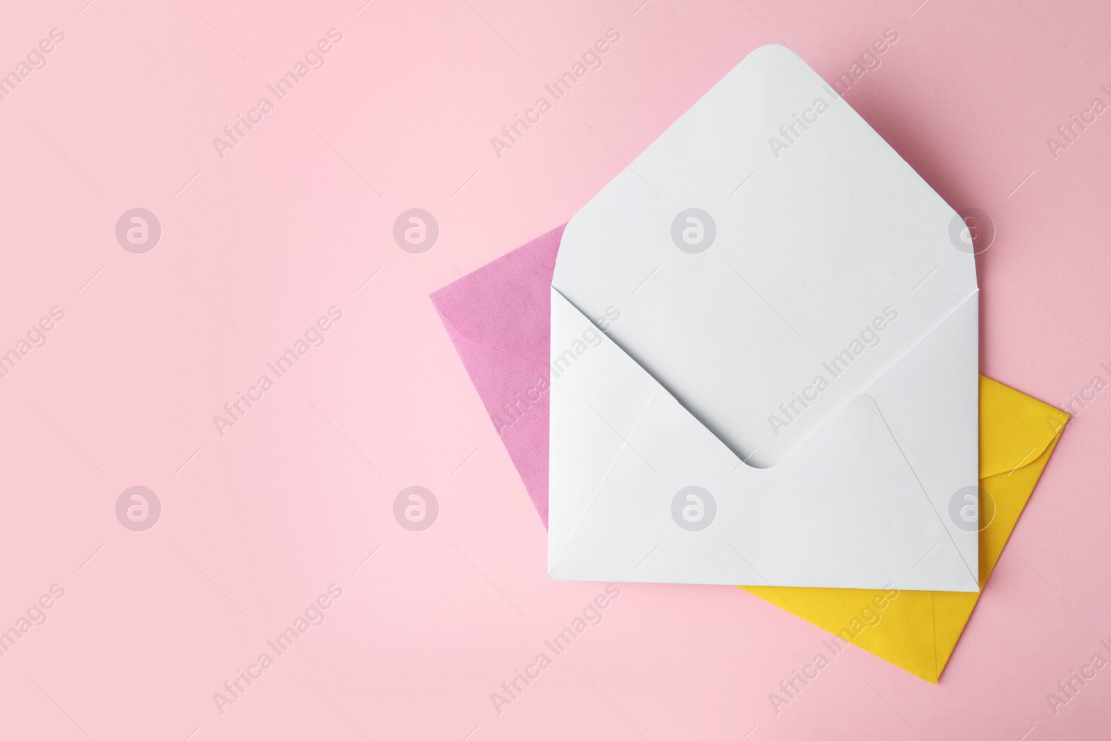 Photo of Colorful paper envelopes on pink background, top view. Space for text