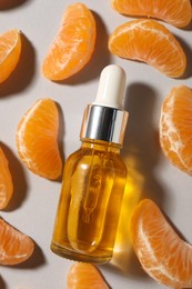 Aromatic tangerine essential oil in bottle and citrus fruit on grey table, flat lay