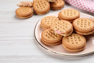 Photo of Tasty sandwich cookies with cream on white wooden table. Space for text