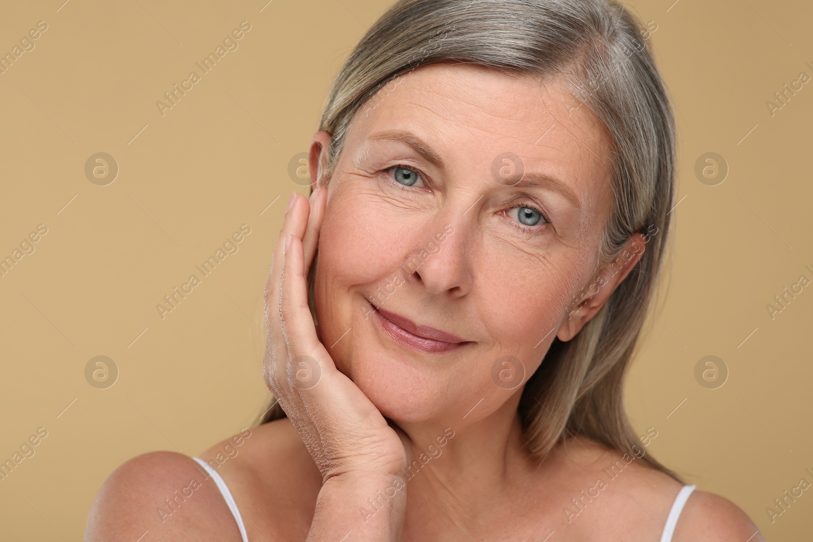 Photo of Portrait of senior woman with aging skin on beige background. Rejuvenation treatment