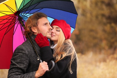 Photo of Young romantic couple with umbrella outdoors on autumn day