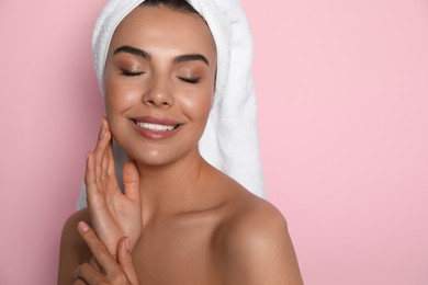 Beautiful young woman with towel on head against pink background