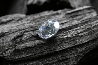 Photo of Beautiful shiny diamond on coal, closeup view